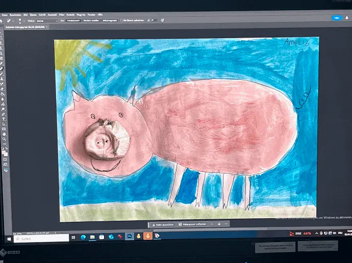 Unser Bildercheck-Service Computer Monitor zeigt in einem Bildbearbeitungsprogramm ein Kinderkunstwerk - ein rosarotes Schweinchen auf der Wiese vor blauem Himmel und gelber Sonne.